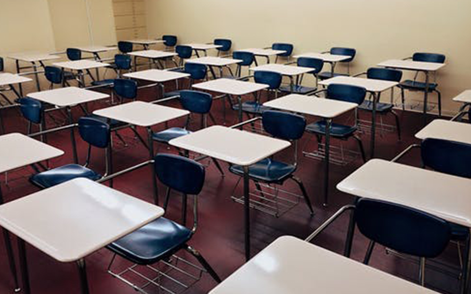 A classroom with empty seats, emphasizing the need for full commitment before applying early decision – The Red Pen