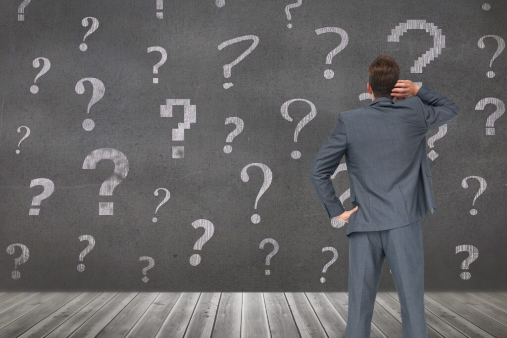 Executive assessing options after being placed on an MBA waitlist, surrounded by query symbols, The Red Pen