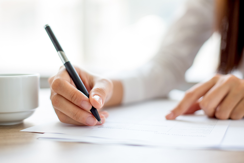 Handwriting on a resume with a cup beside it, representing the process of perfecting a business school application – 5 Tips to Help You Create the Perfect Business School Resume | The Red Pen