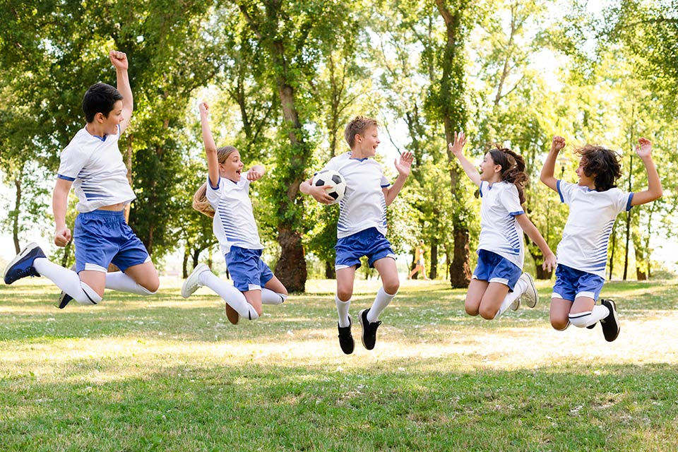 Energetic schoolchildren in sports uniform jumping joyously, highlighting extracurriculars at Swiss boarding schools - The Red Pen