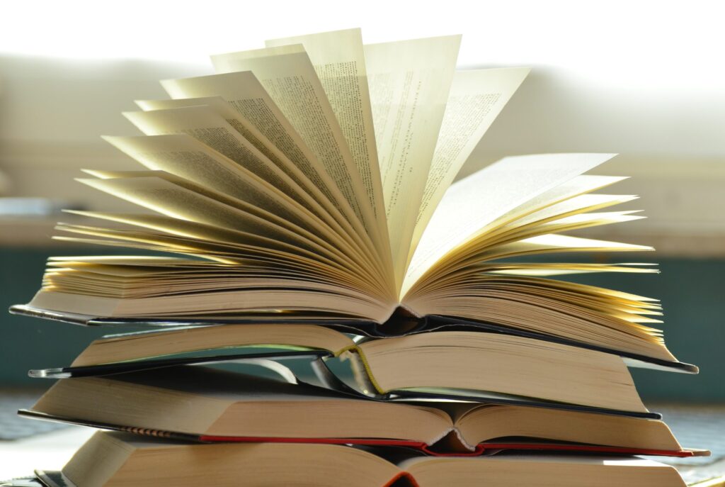 Open books stacked in natural light symbolizing the depth of A Level studies - The Red Pen