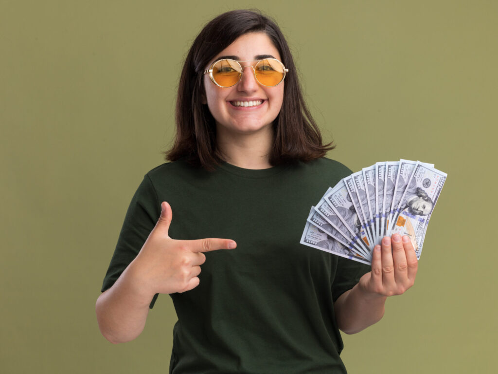 Cheerful young woman with money, demonstrating smart budgeting tips for studying abroad - The Red Pen