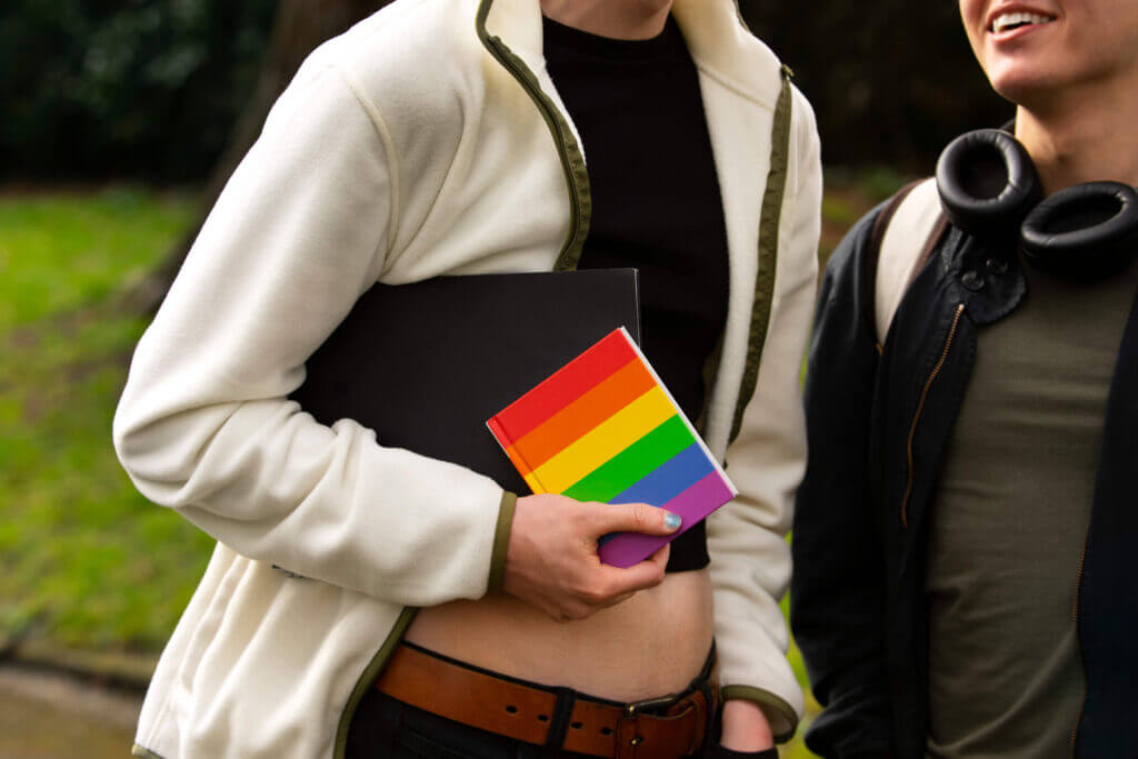 Supportive academic environment for LGBTQ+ students, illustrated by a rainbow notebook - The Red Pen